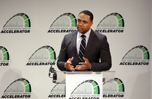 Black man speaking at podium.