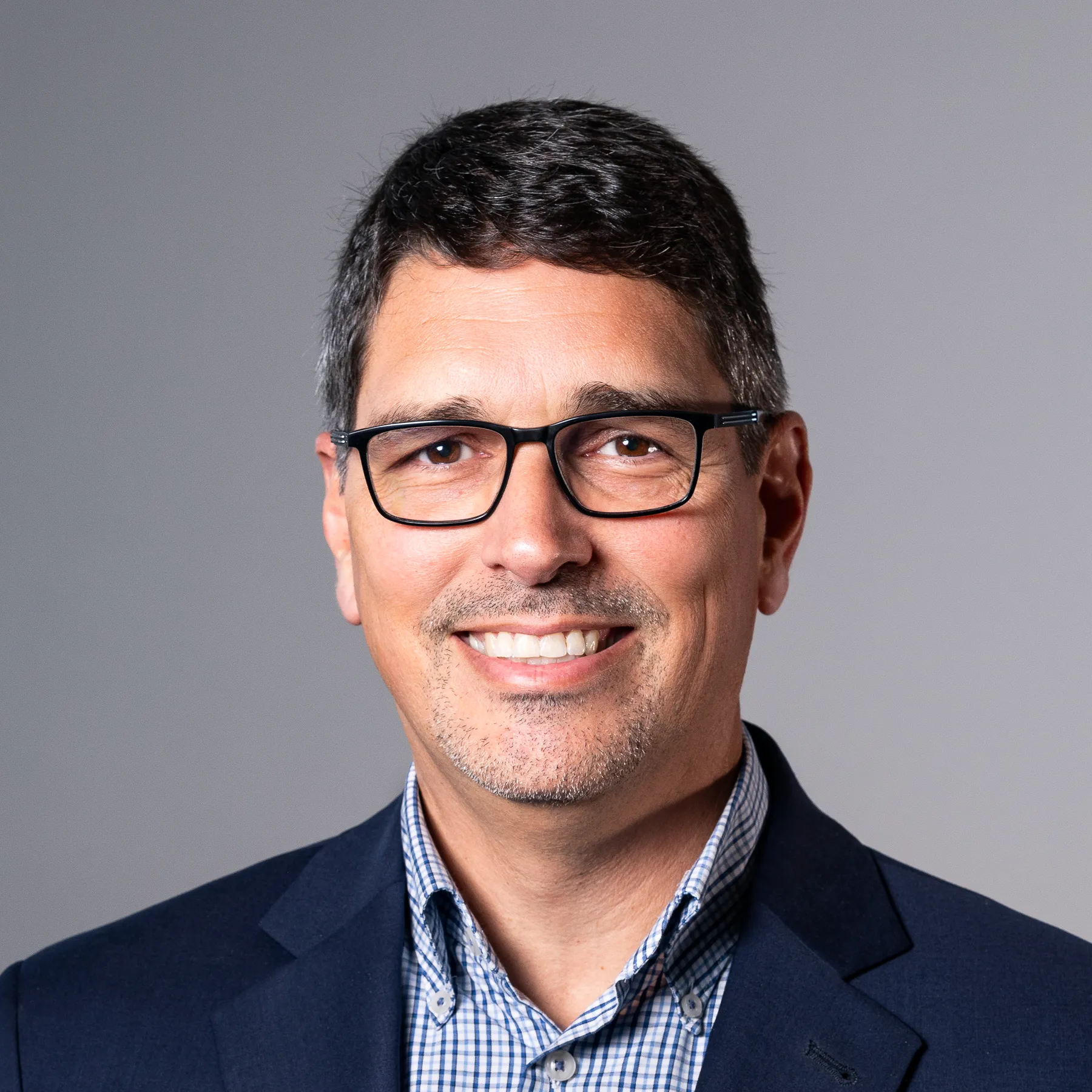 David Horrocks, wearing glasses and a navy blazer over a blue plaid shirt.